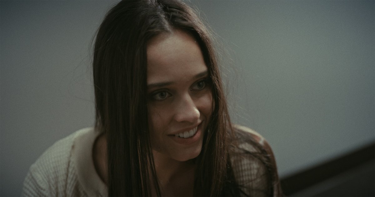 Close-up of a smiling young woman with long dark hair looking down and to the side