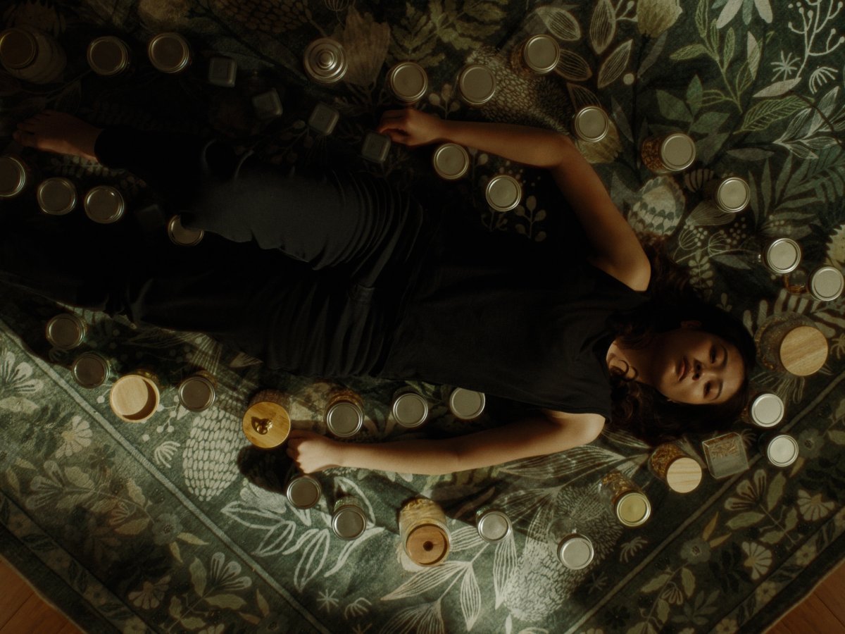 Overhead shot of a woman lying on a floral rug surrounded by scattered mason jar lids